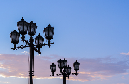 Silhouettes of black wrought iron street lamps against summer sunset sky.の写真素材