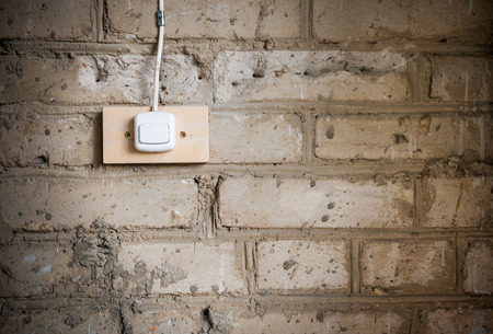Grunge background. Close-up part of old dirty brick wall, stained of cement, and electric switch attached to it.の写真素材