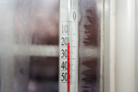 Close-up  view through frozen window from house to the outdoor thermometer which showing subzero temperature.の写真素材
