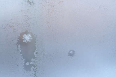 Christmas background. Frosty winter window glass, two thawed spots with snowflakes inside and copy space.の写真素材