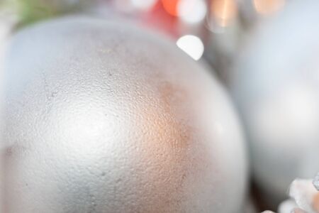Abstract blurred christmas background. Close-up silver ball with golden glare in foreground and golden bokeh on background and copy space.の写真素材