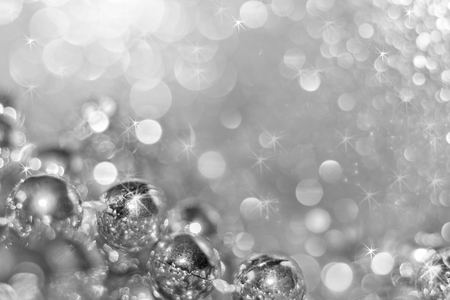 Abstract silver christmas black and white background with soft focus. Round beads on the bottom left and beautiful shining bokeh with asterisks.の写真素材