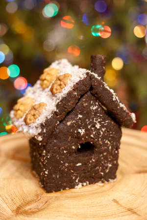 House made of crushed dried prunes, nuts, dates is standing on round wooden board on background of colorful bokeh.の写真素材