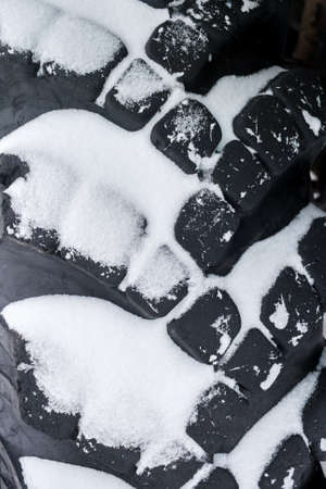 Close-up snow-covered black big automobile tire.の写真素材