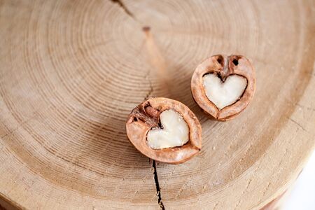 Close-up two halves of walnut in shape of heart on wooden background with copy space. Top view.の写真素材