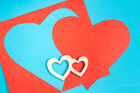 Big red heart carved from paper sheet and two  small wooden hearts are lying on bright azure background. Top view.の写真素材