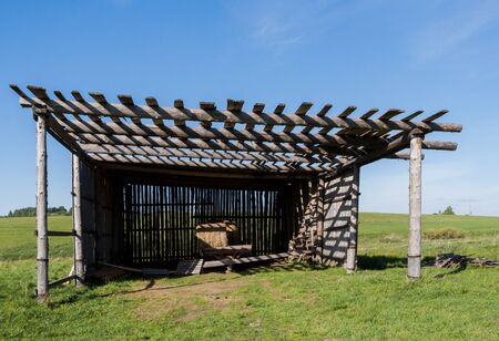 Old wooden shed for hay in the open green field.の写真素材