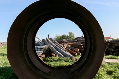 Metal pipe of large diameter, through which is visible heap of piled logs.の写真素材