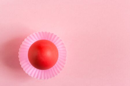 Easter background. One red egg in pink cupcakes mold on a pink background with copy space.の写真素材
