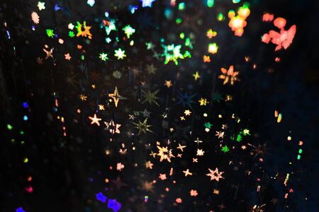 Pattern with multicolored stars on black textured holographic paper.の写真素材
