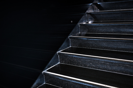 Geometric abstraction. Black granite staircase going diagonally upward reflecting in black wall with copy space.の写真素材