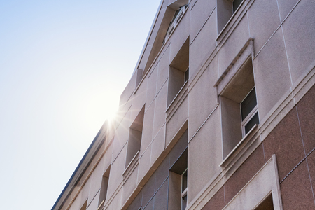 The suns rays shining  facade of a modern beige building.