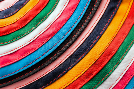 Circular handmade cloth stitched from multicolored stripes as background.