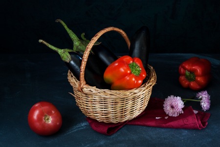 Vegetables in wicker basket and on dark table on dark background.の写真素材