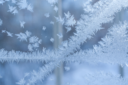 Tracery frosty pattern of two intersecting stripes on winter blue window.の写真素材