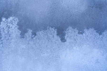 Graceful wavy winter frosty icy pattern similar sea foam on window pane.の写真素材