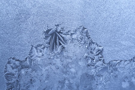Frozen winter glass pane with frosty pattern and copy space.