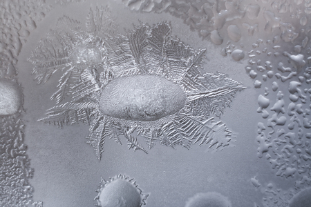 Close-up slightly melted large frozen water drop and icy crystal patterns around it.の写真素材