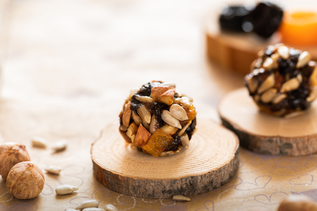 Handmade energy balls on wooden saw cuts and ingredients for their preparation on paper background.の写真素材