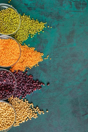 Emerald-green background with scattered on it from round glass cups legumes.の写真素材
