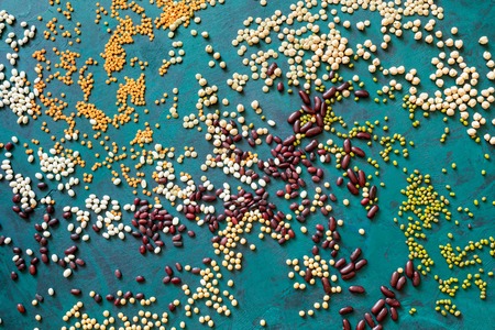 Top view of chaotically scattered beans on emerald green background.の写真素材