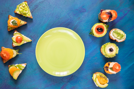 Top view vegetarian sandwiches and round green plate on blue background.の写真素材