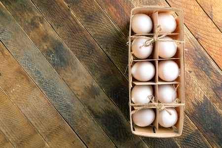 Open eco-friendly wooden box with eggs on wooden table.