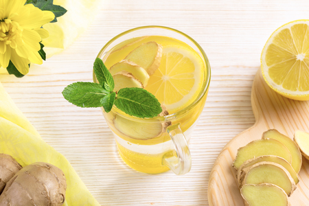 Glass of water, infused with lemon and ginger on light wooden table.の写真素材