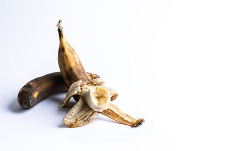 Two overripe blackened ugly bananas on white background.の写真素材