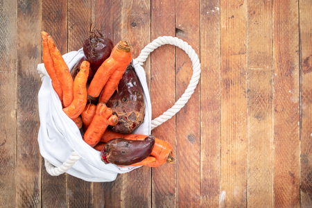 White linen bag with washed non-standard  ugly vegetable on wooden table.の写真素材