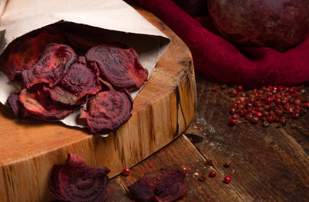 Homemade beetroot chips in paper bag on cut on wooden table.の写真素材