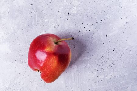 One ugly ripe red  apple on grey concrete background.の写真素材