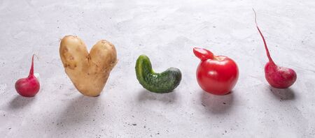 Five ugly vegetables are standing in row on grey concrete background.の写真素材