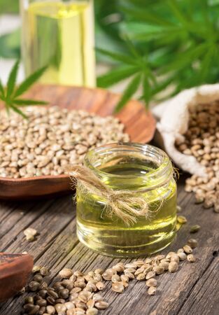 Composition with hemp products. Cannabis oil, seeds and green leaves on old wooden board.の写真素材