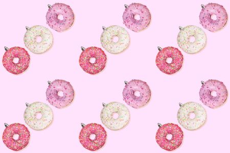 Christmas decorations. Festive creative seamless pattern of diagonal rows of colorful donuts as Christmas tree toys on gentle pink background.の写真素材