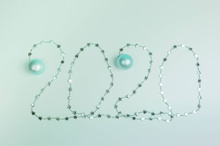 Christmas festive layout in trendy Neo Mint color. Creative numbers 2020 of shiny Christmas garland with small stars and Christmas balls. Top view, flat lay.の写真素材