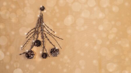 Creative Christmas mockup. Christmas tree of painted bronze twigs with cones on golden backdrop with...