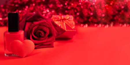 Red festive Valentines day or mothers day banner. Nail polish, textile heart, rose, gift box on red background with bokeh. Women's beauty and care concept. Copy space for text.の写真素材