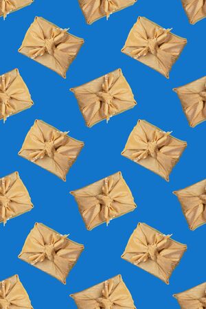 Vertical seamless pattern of gift boxes, wrapped in golden fabric in japanese Furoshiki technique on trendy Classic Blue background. Valentine's day, mother's day, Women's day or Birthday. Zero Waste concept. Top view, flat lay.の写真素材