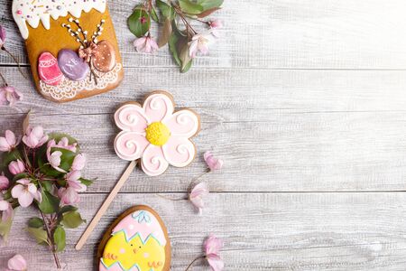 Close-up festive Easter decorations laid out on wooden background. Pink Apple tree branches and...