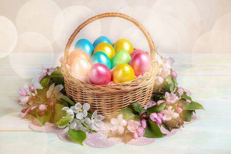 Easter festive composition of basket of painted multicolored Easter eggs and sprigs of white and...