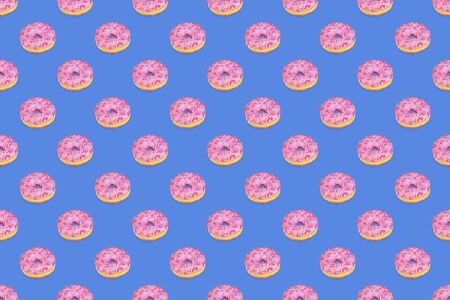 Fashionable seamless pattern of traditional doughnuts with lilac glaze on trendy classic blue background. Regular rhythmic pattern. Top view, flat lay. Horizontal orientation.の写真素材