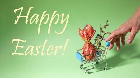 Female hand pushe small basket with Easter egg wrapped in red paper and willow twigs on neo mint...