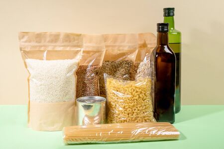 Stock of food products in paper and cellophane packagings on beige-green. Cereals, pasta, oil...