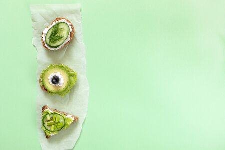 Three vegetarian sandwiches with cucumber, avocado, greenness, cheese and olives on vertical...