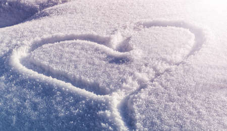Large heart drawing on white snow with winter sunlight. Festive winter snowy background with painted...