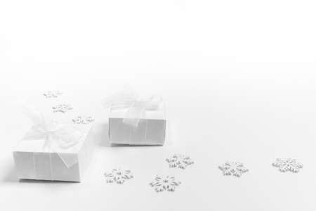 Arrangement of white Xmas Decorations: snowflakes and two DIY gift boxes on white. Christmas modern...