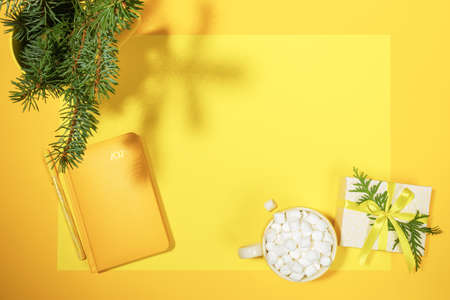 Xmas workspace in yellow color. Yellow notepad - organizer on 2021, cup of coffee with marshmallows,...