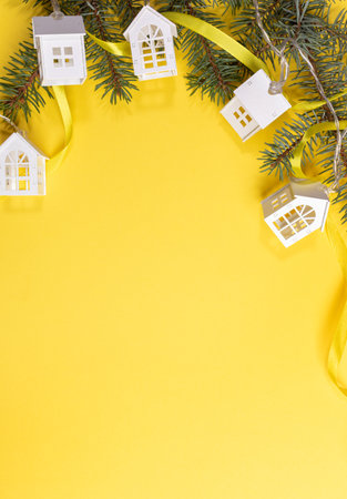 Christmas, New Year festive background with green fir branches, Xmas lights white lodges on yellow. Top view. Christmas holiday decorations. Copy space for text. Vertical orientation.の写真素材