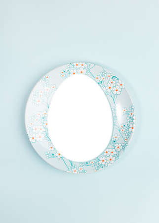 Easter creative festive minimal layout with copy space in egg shape on plate on center of light blue backdrop.の写真素材